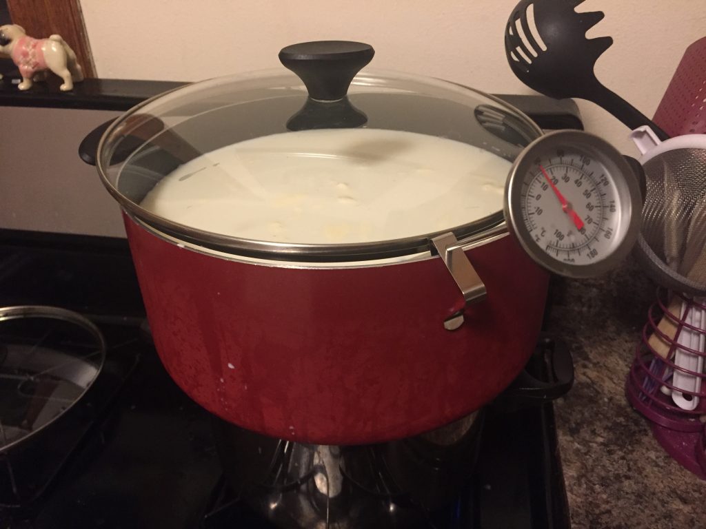 A large red pot of milk on a gass stove